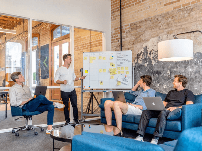 Four men meeting around whiteboard