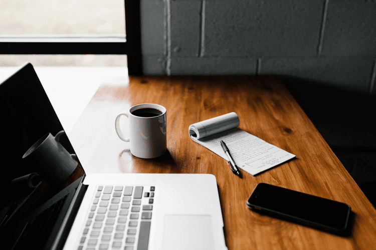 Laptop, coffee mug, and pad of paper