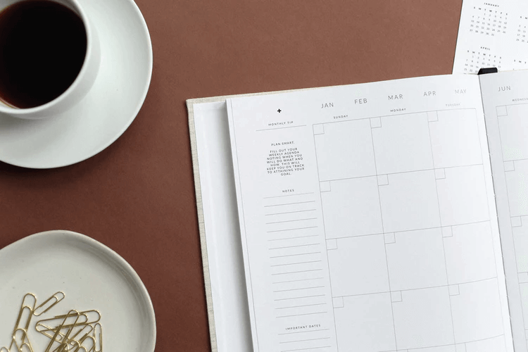 Desk with a calendar, cup of coffee, and paper clips 