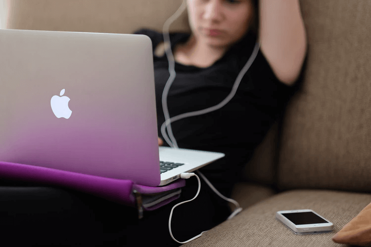 Girl wearing earbuds looking at her laptop