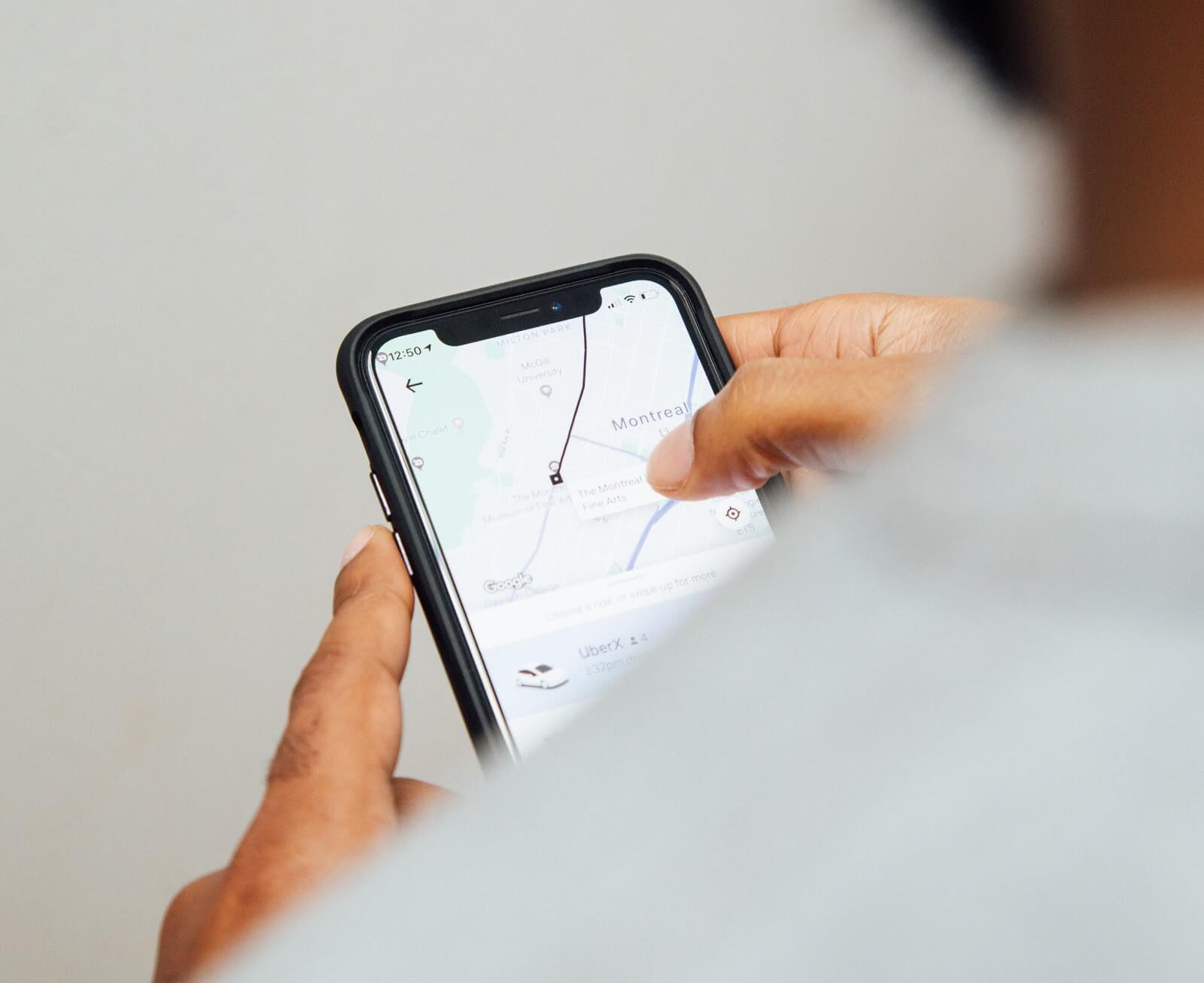 Uber Complaints: over-the-shoulder view of a man looking at his Uber app