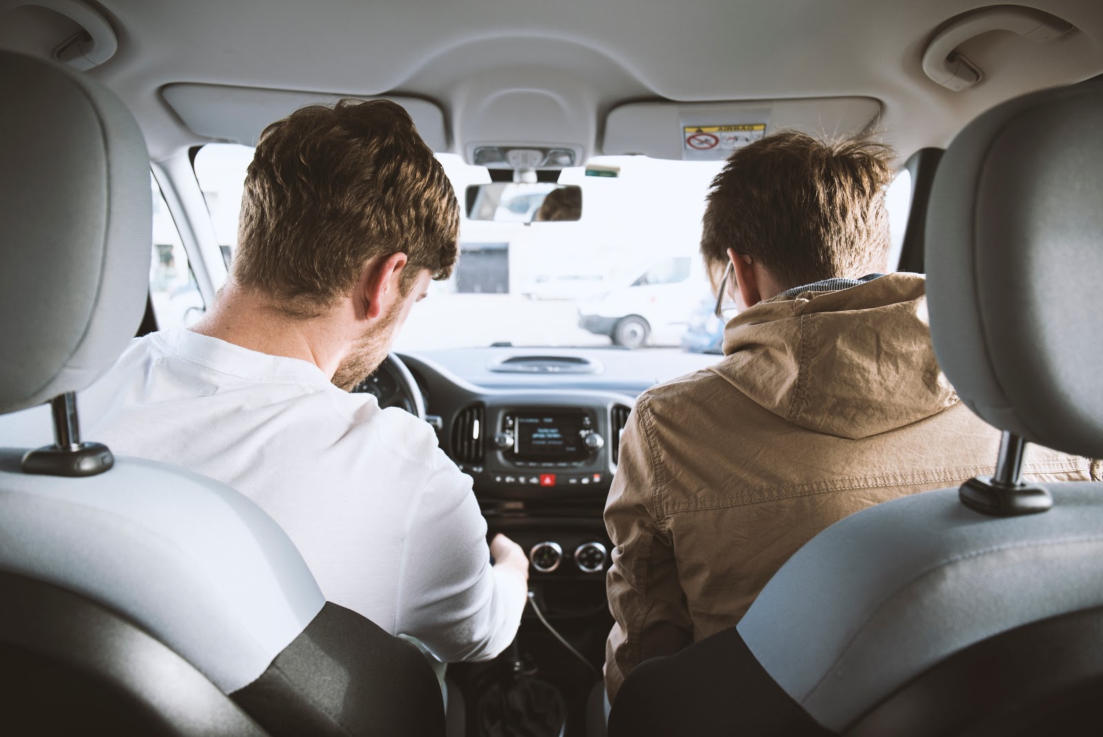 Two guys in a vehicle looking at the dashboard