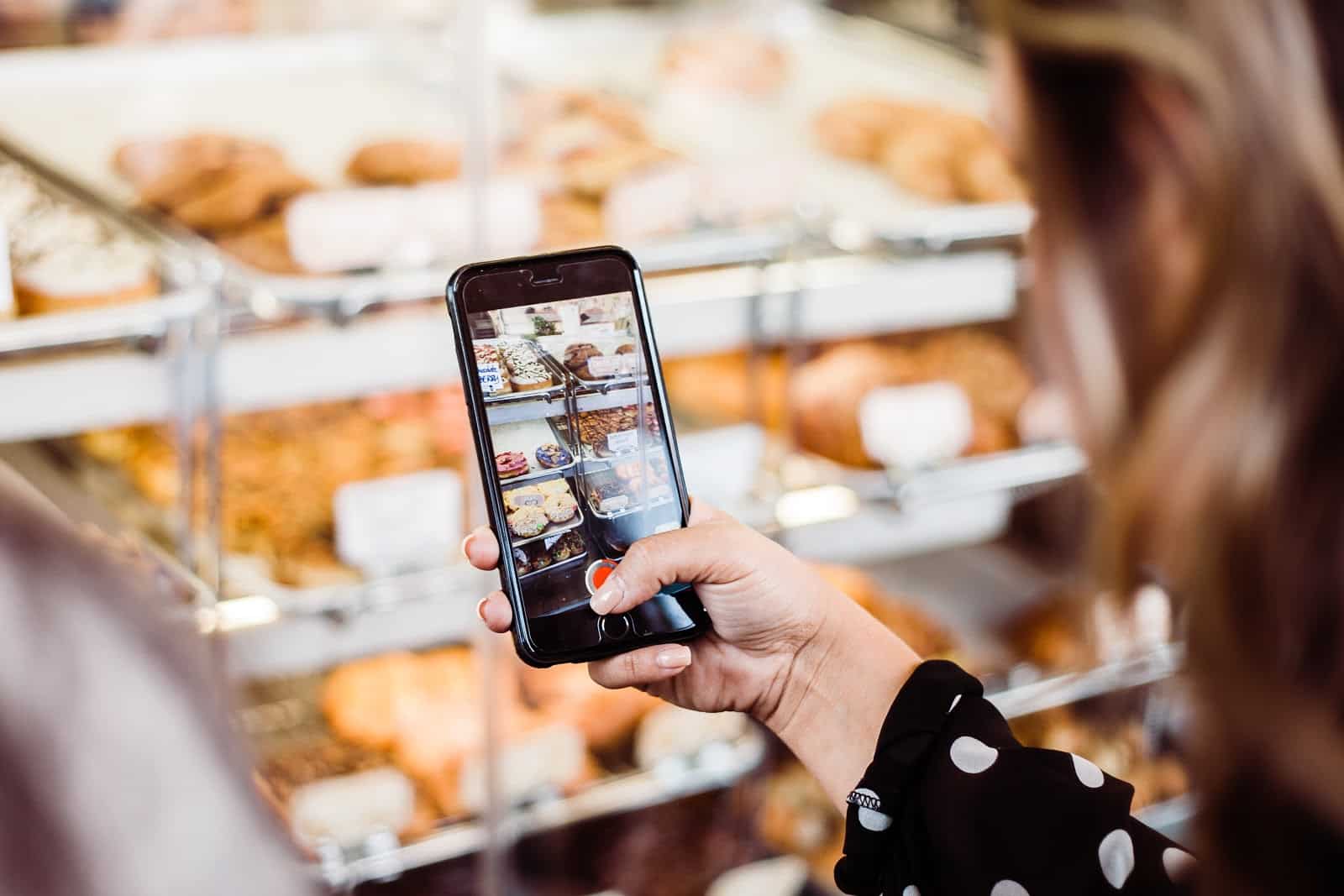 Woman taking photo of bakery items on iPhone