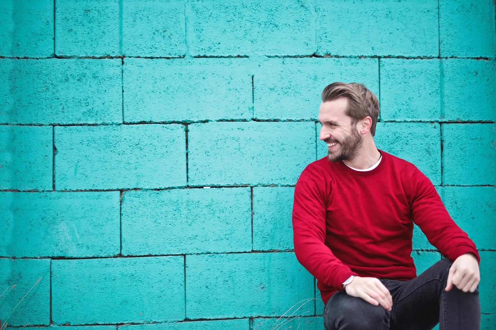 man sitting against wall laughing