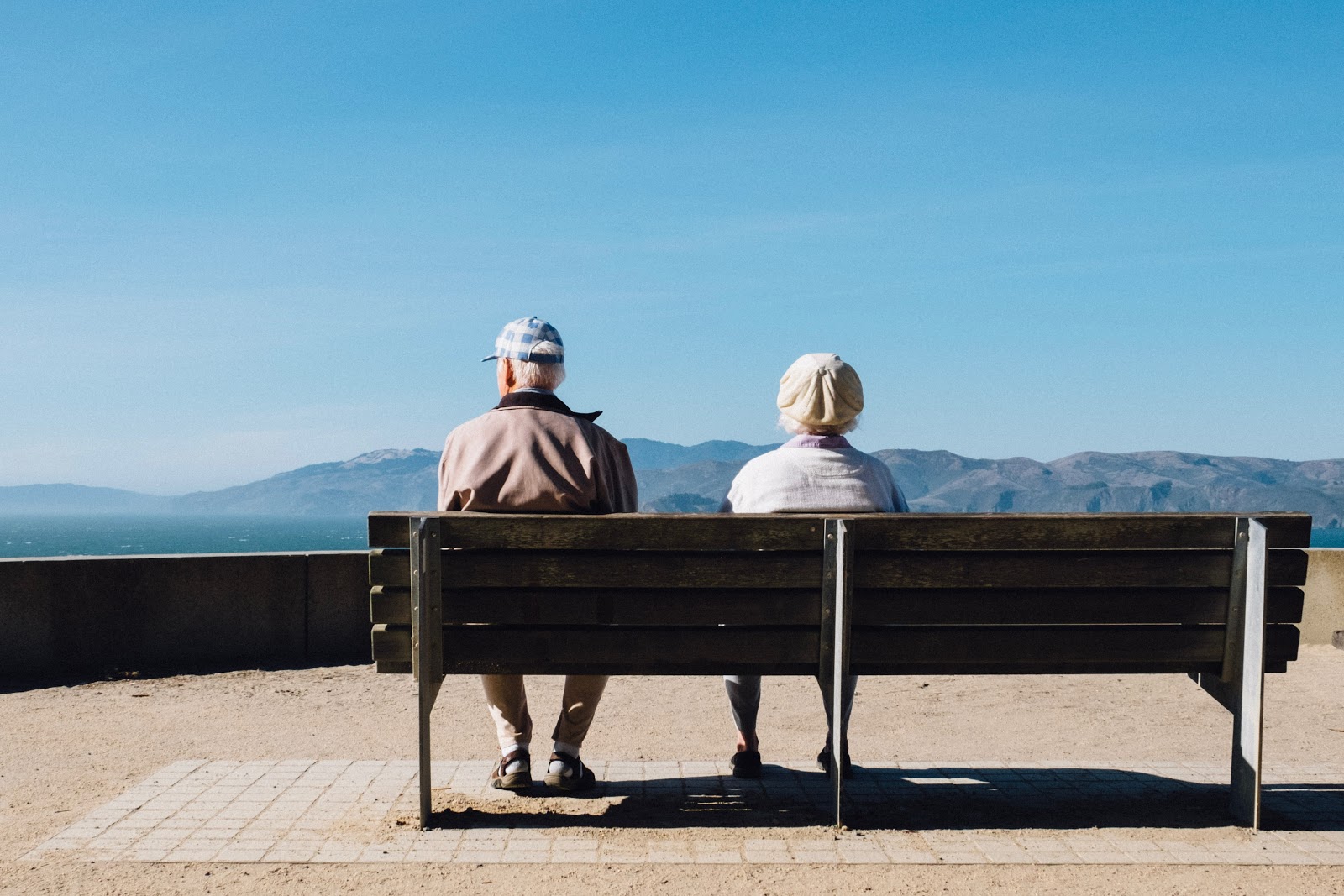 Elderly couple sitting on a bench looking out at mountains