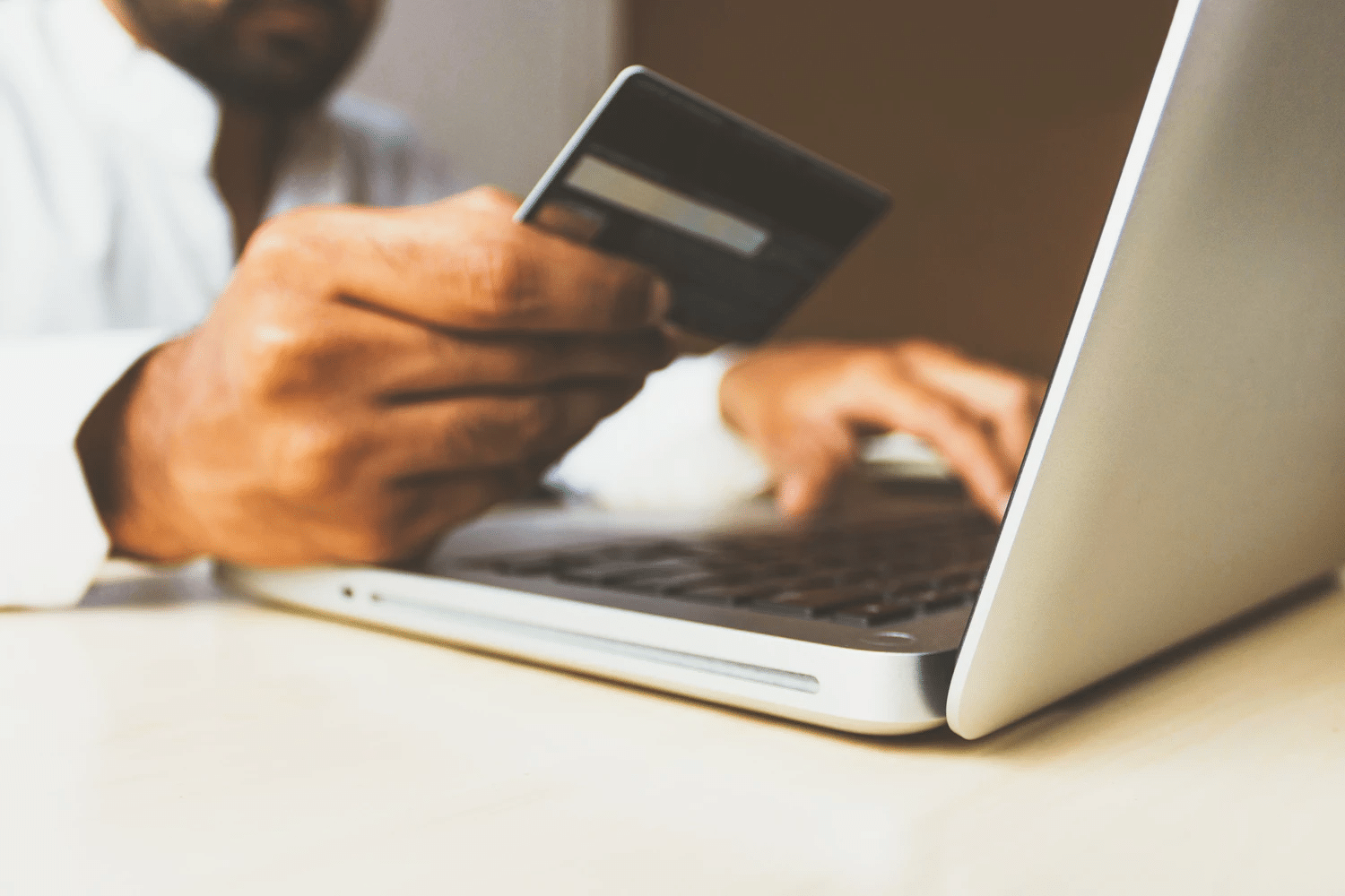 Airbnb vs. Vrbo: Hands hold credit card in front of laptop