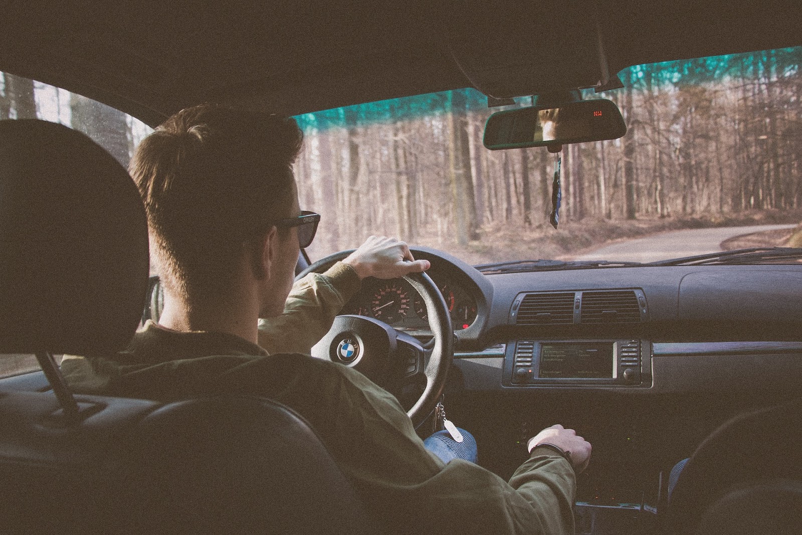 Young man driving a BMW in the barren woods