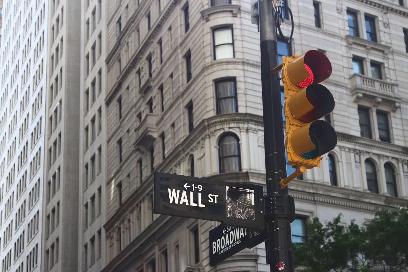 Stash App: Street sign at the corner of Wall Street and Broadway in New York with building in the background