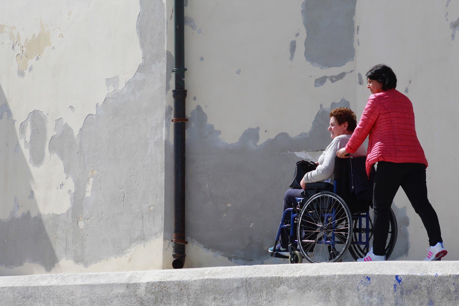 Elderly woman in a wheelchair being helped by a caregiver