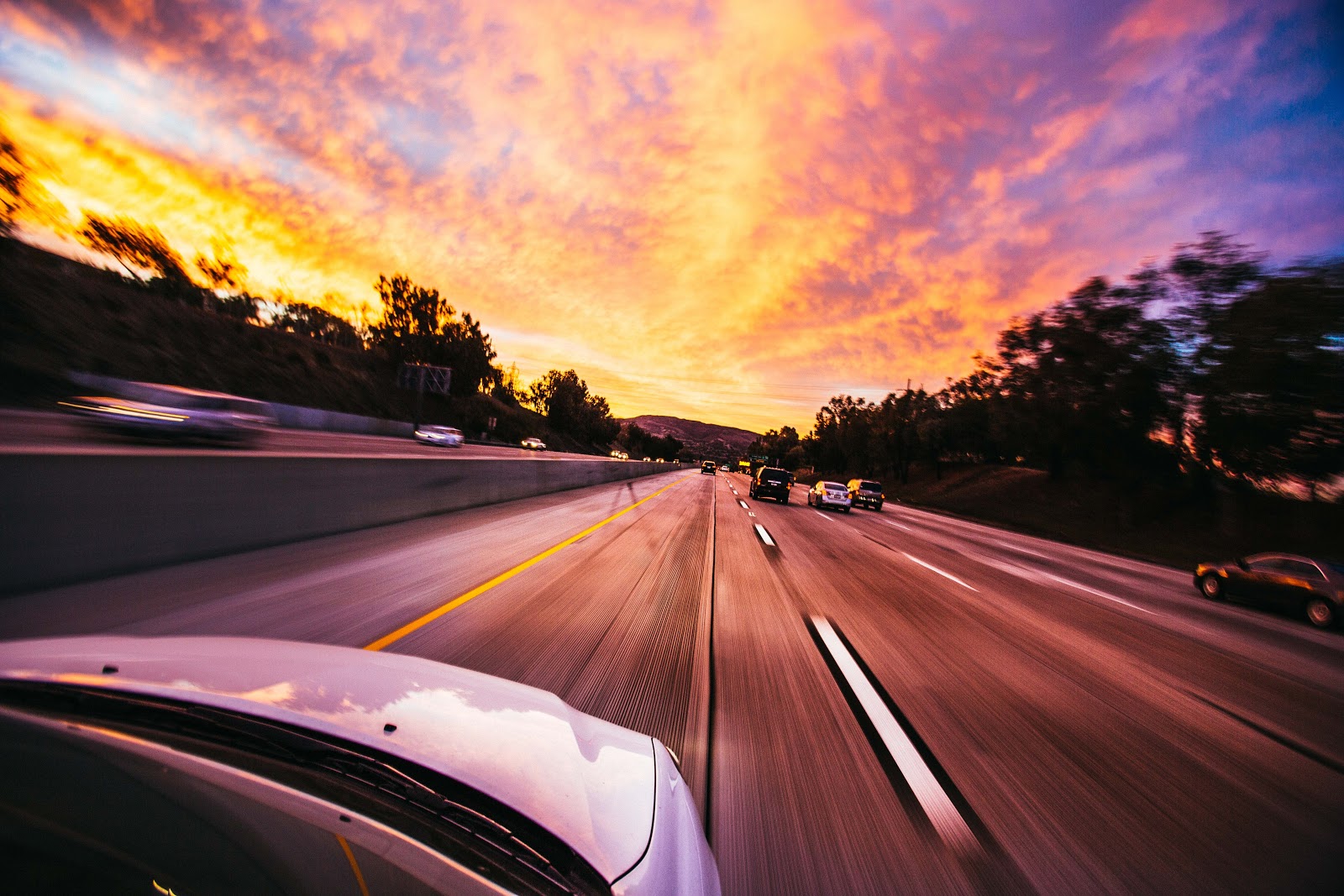 how to change a headlight: car driving at sunset with colorful sky