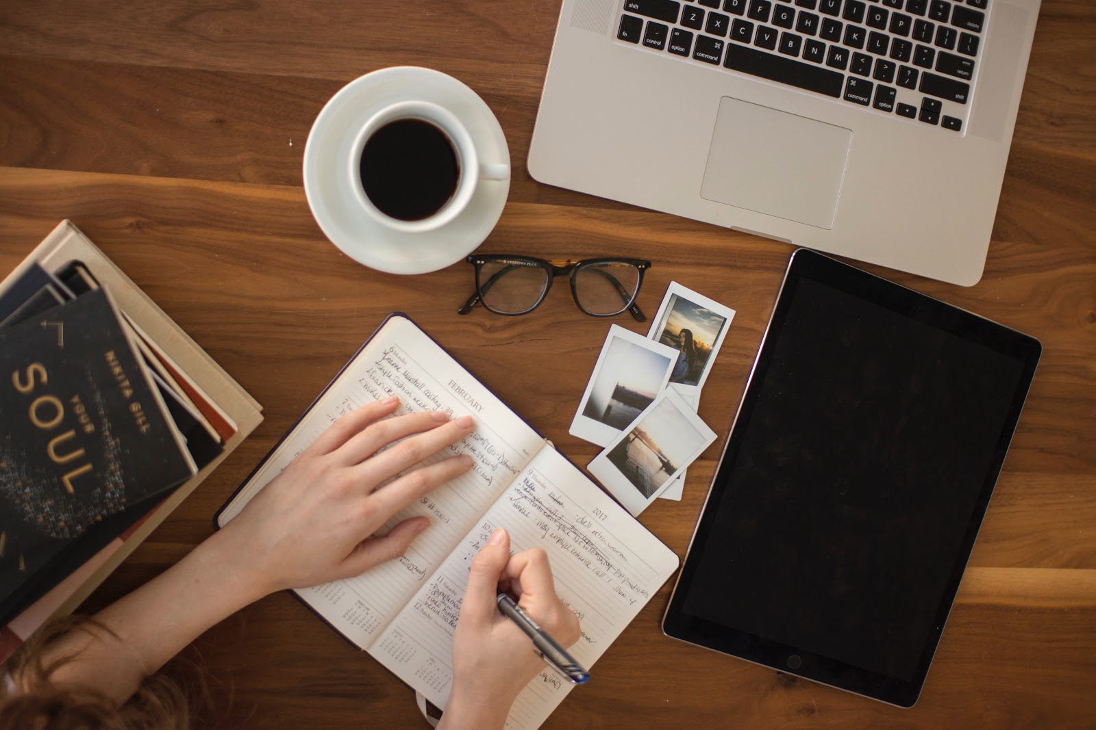 writing in notebook with coffee and laptop on table