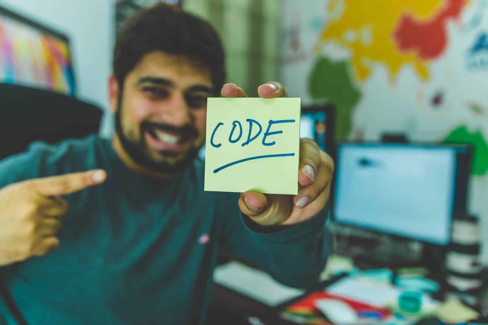 man holding sticky note with the word "code"