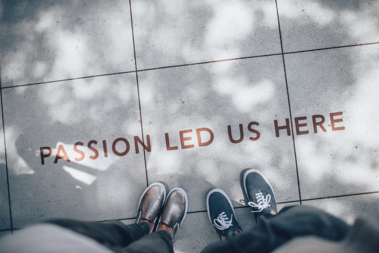 people standing on sidewalk with "passion led us here" on the ground