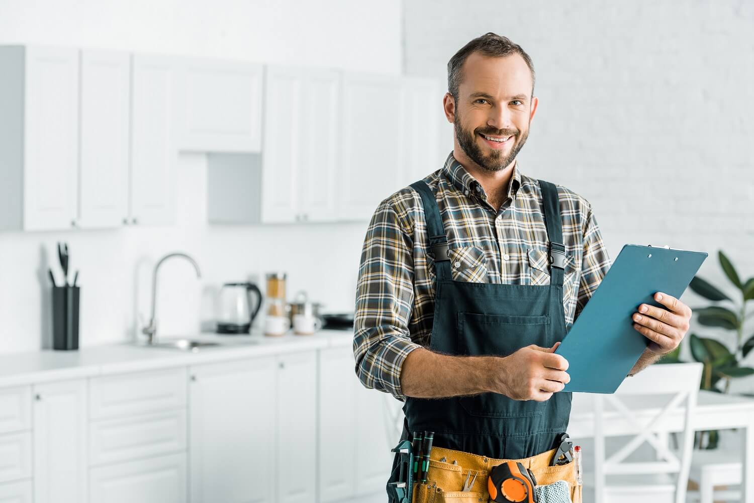 Smiling handsome plumber holding clipboard