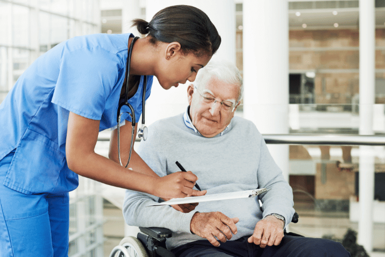 A young female caregiver discussing paperwork with an elderly patient in a wheelchair