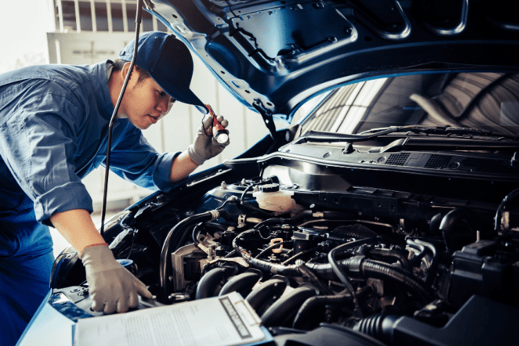 A Mechanic man holding a flashlight and checking car engine