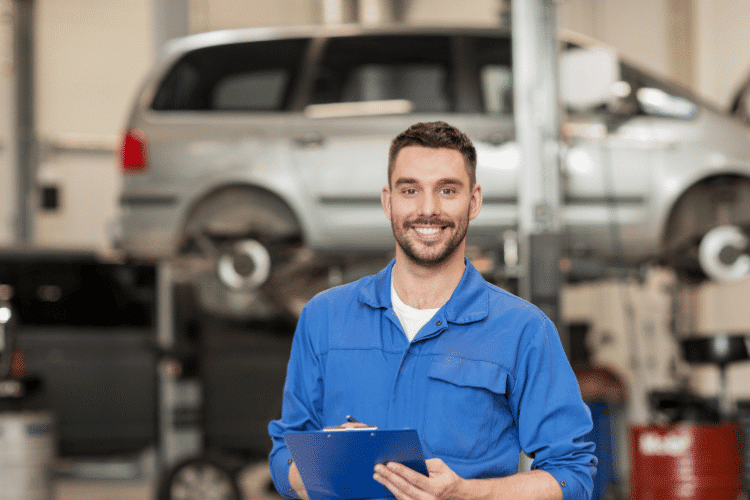 A happy Mechanic man holding a blue clipboard in a car repair center