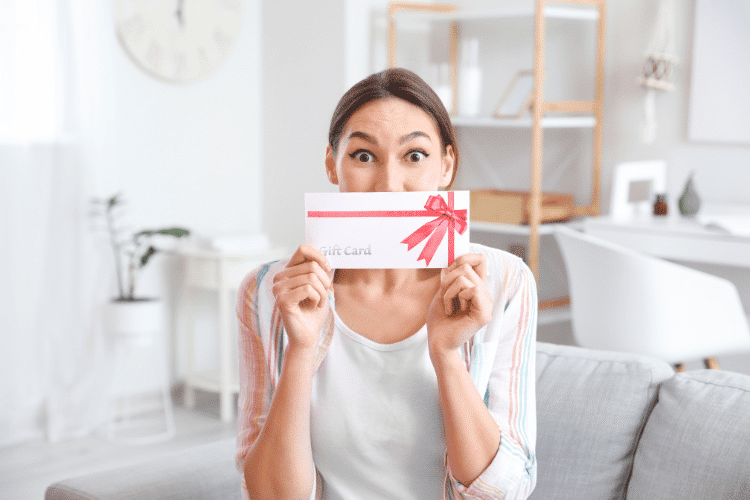 A happy woman with gift card at home