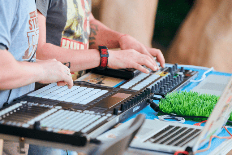 Close-up of two music makers working on a DJ set board and laptop