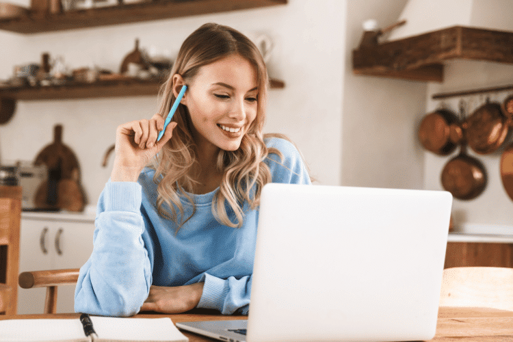A smiling young woman working on her laptop at home