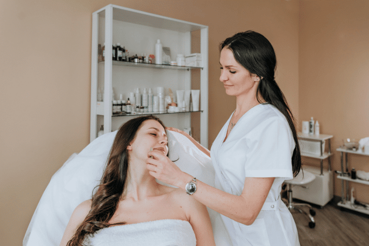 An esthetician doing a facial cleansing for her client