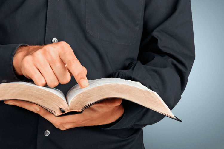 Close-up of ordained minister reading in a bible book